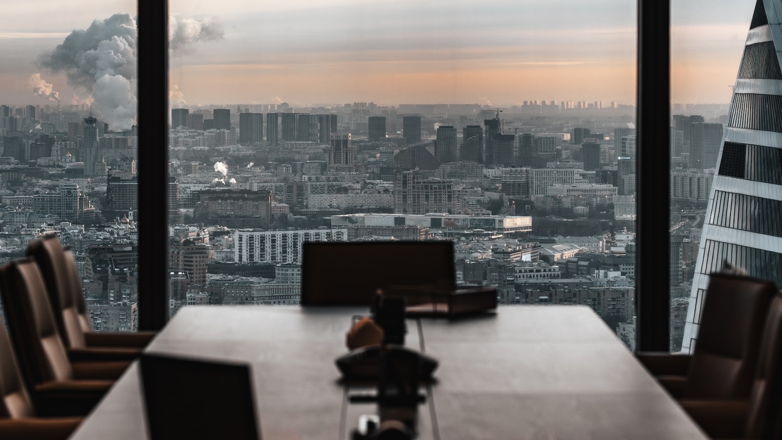 Sunset light flooding a high-rise conference room overlooking a city skyline.