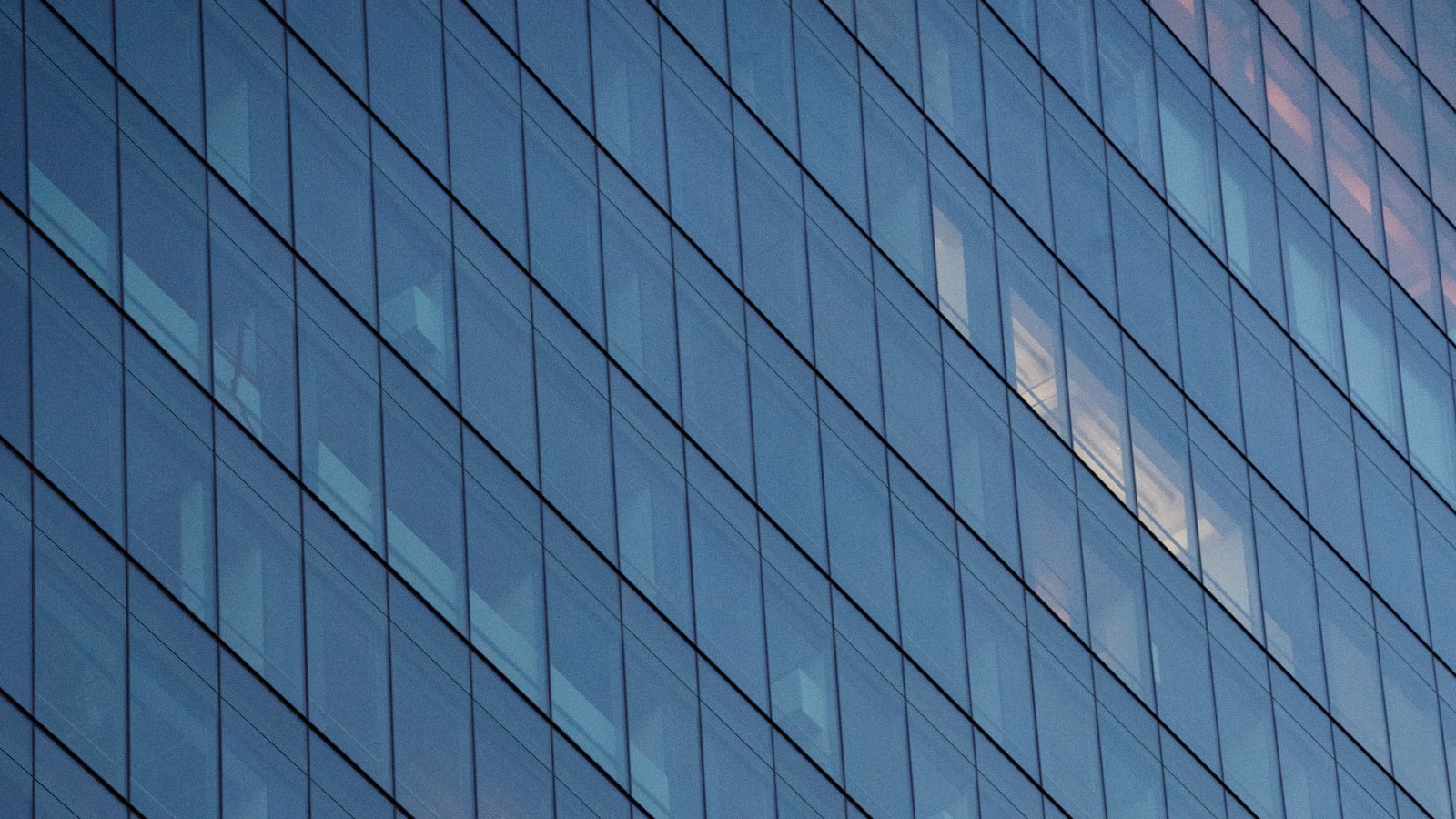 Modern glass building facade with reflective blue-tinted windows.